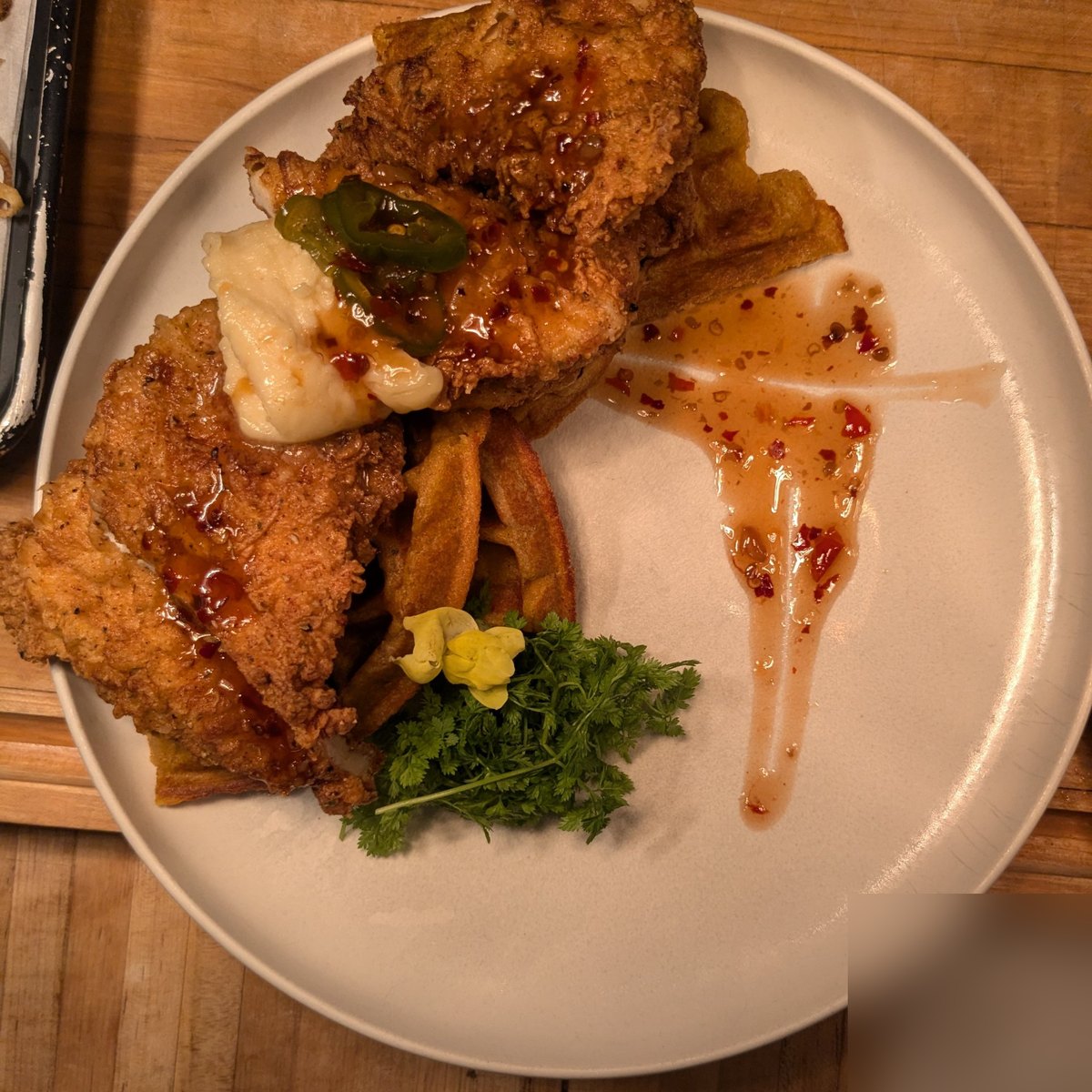 Cajun fried chicken over candied yam waffles with maple syrup and candied jalapeños