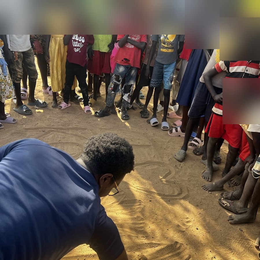 Ace drawing in the sand as he preaches to kids on a mission trip in Kenya