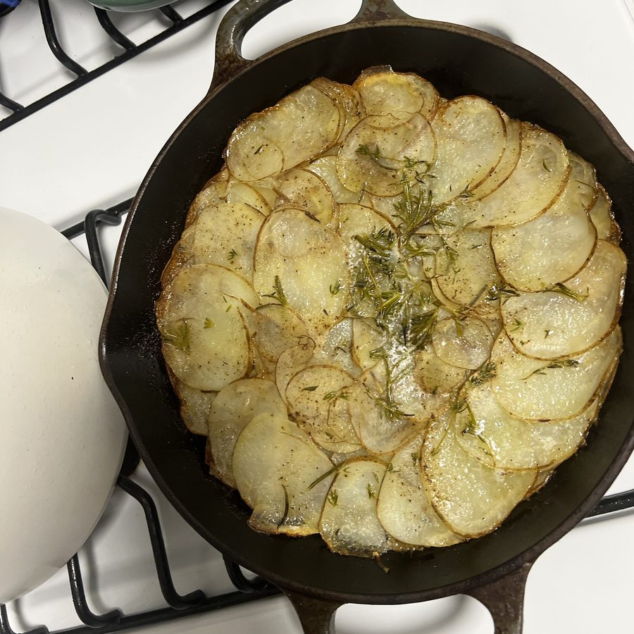 Potatoes layered with rosemary in a cast-iron pan